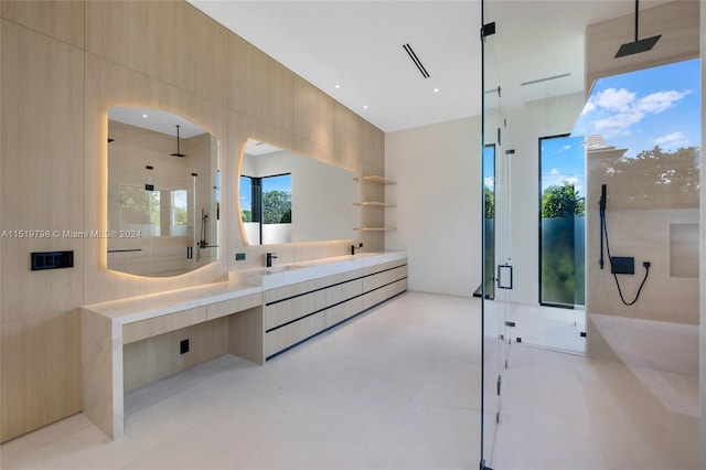 bathroom featuring double vanity, concrete floors, a shower stall, and a sink