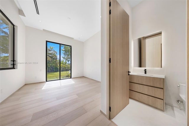 interior space featuring a sink, light wood finished floors, a high ceiling, and access to outside