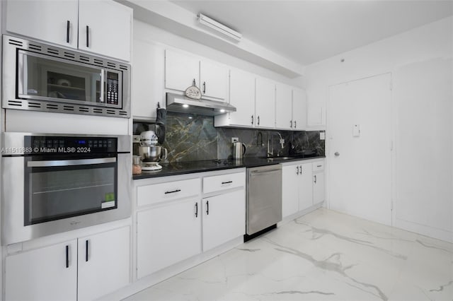 kitchen featuring white cabinetry, backsplash, light tile flooring, sink, and stainless steel appliances