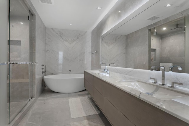 bathroom featuring tile walls, double vanity, tile patterned floors, and a tub