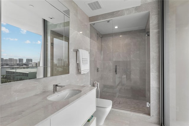 bathroom with a shower with door, tile walls, vanity, and toilet