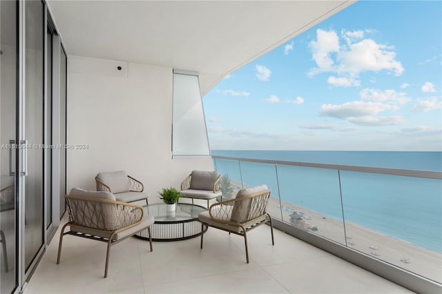 balcony featuring an outdoor hangout area, a beach view, and a water view