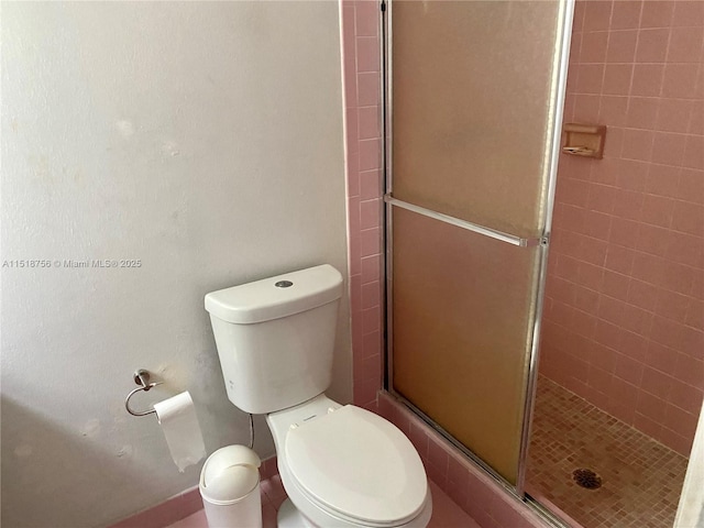 bathroom featuring a stall shower and toilet