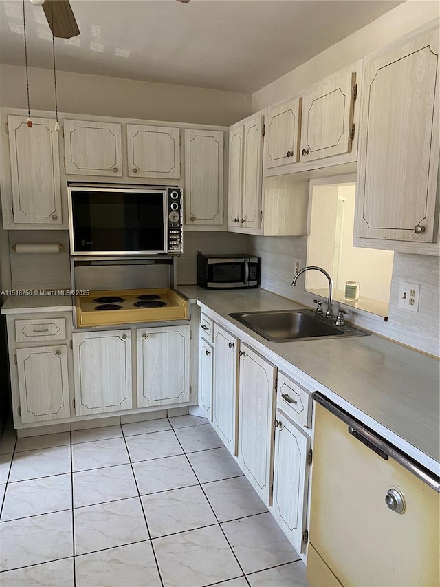 kitchen with stainless steel microwave, white dishwasher, light countertops, stovetop, and a sink