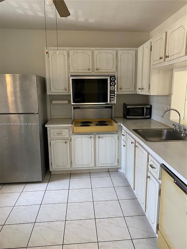 kitchen with light tile patterned floors, ceiling fan, appliances with stainless steel finishes, light countertops, and a sink