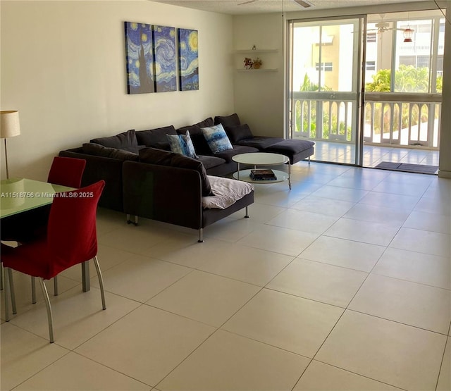 tiled living area featuring expansive windows and a ceiling fan