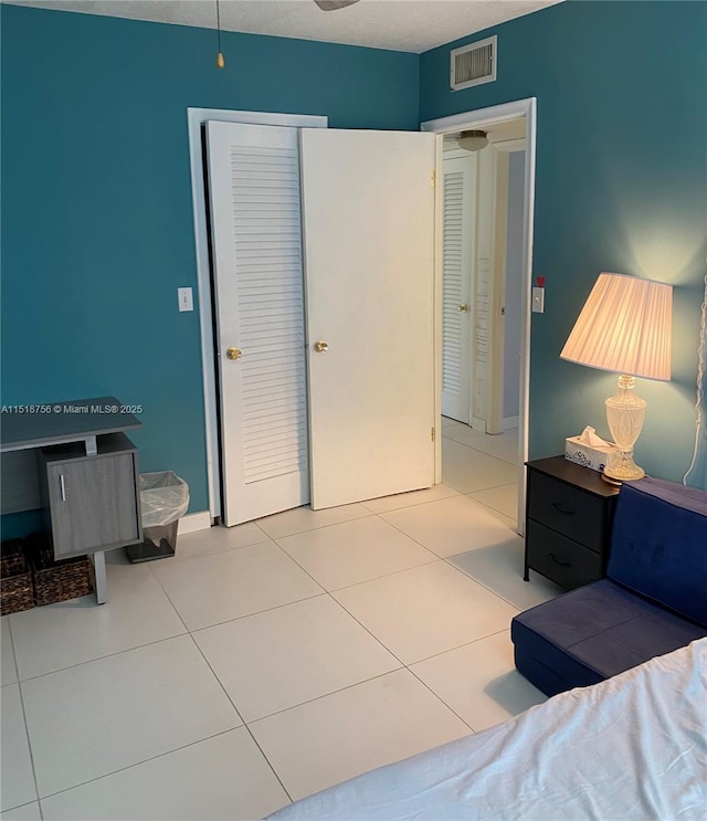 bedroom featuring a closet, visible vents, baseboards, and tile patterned floors