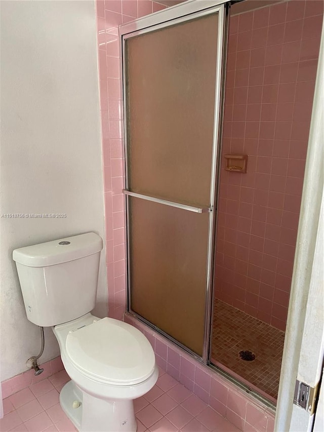 full bath with a stall shower, toilet, and tile patterned floors