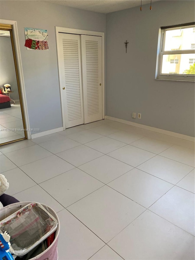 unfurnished bedroom with baseboards, a closet, and tile patterned floors