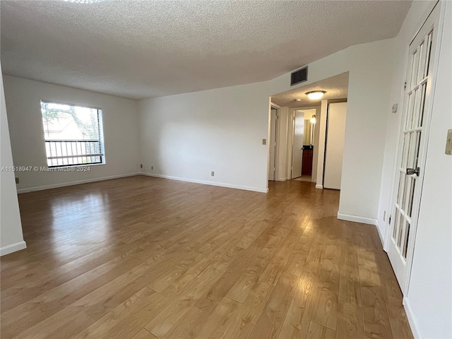 empty room with hardwood / wood-style floors and a textured ceiling