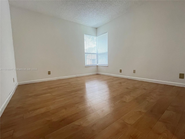 empty room featuring a textured ceiling and light hardwood / wood-style flooring