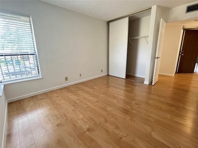 unfurnished bedroom with light hardwood / wood-style flooring and a textured ceiling