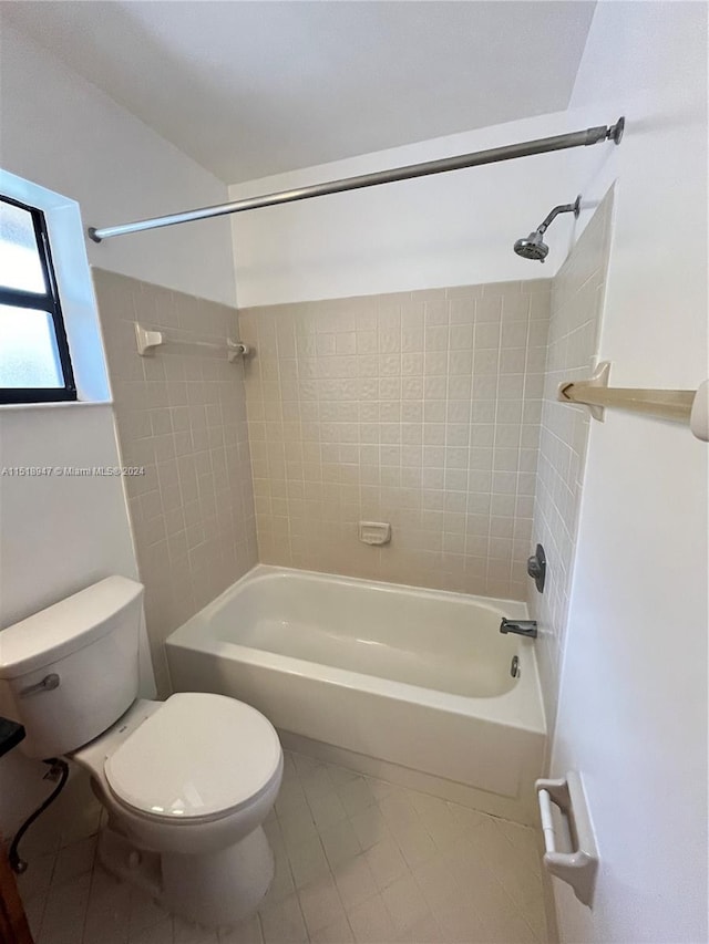 bathroom featuring tiled shower / bath, toilet, and tile floors