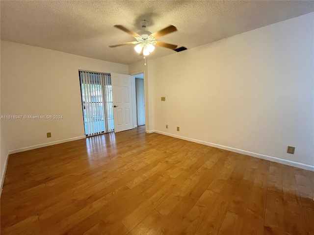 spare room with light hardwood / wood-style floors, ceiling fan, and a textured ceiling