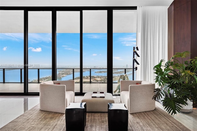 living room with plenty of natural light, a water view, and a wall of windows