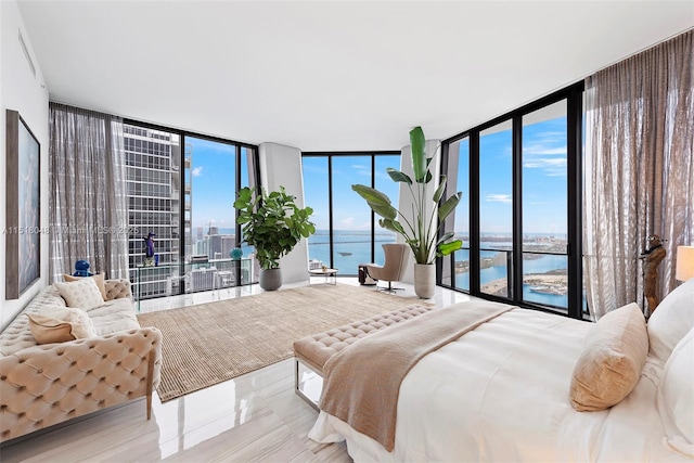 bedroom with floor to ceiling windows, a water view, and multiple windows