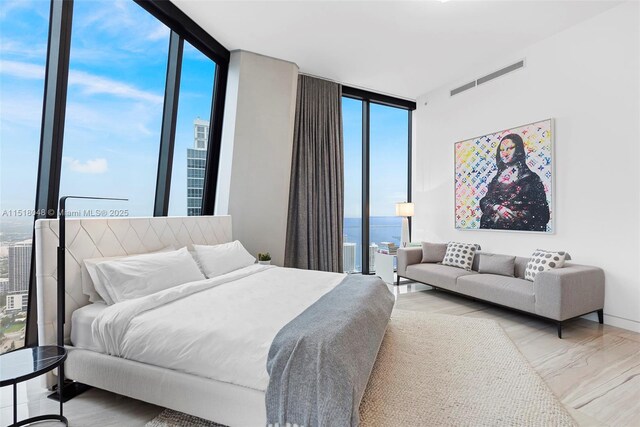 bedroom featuring multiple windows, a water view, and floor to ceiling windows