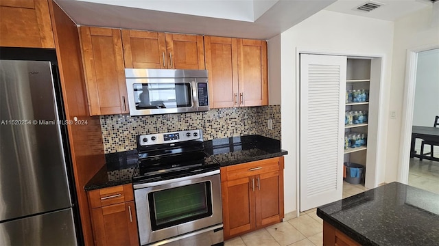 kitchen with dark stone countertops, light tile flooring, and stainless steel appliances