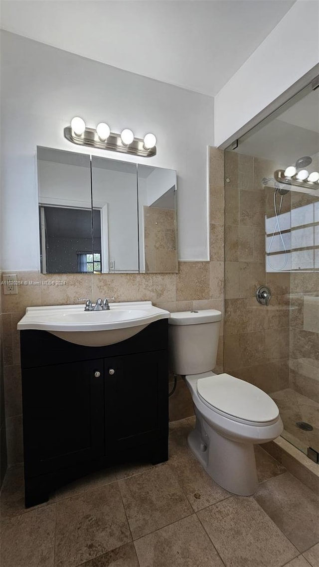 bathroom featuring vanity, tile flooring, toilet, and tile walls