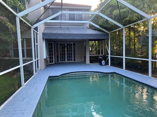 view of swimming pool with a grill, a patio area, and glass enclosure