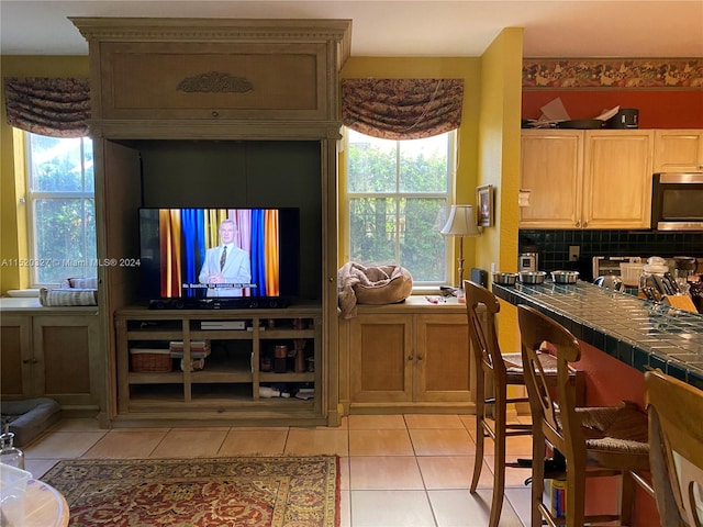 kitchen with light tile floors, a kitchen breakfast bar, tasteful backsplash, and tile countertops