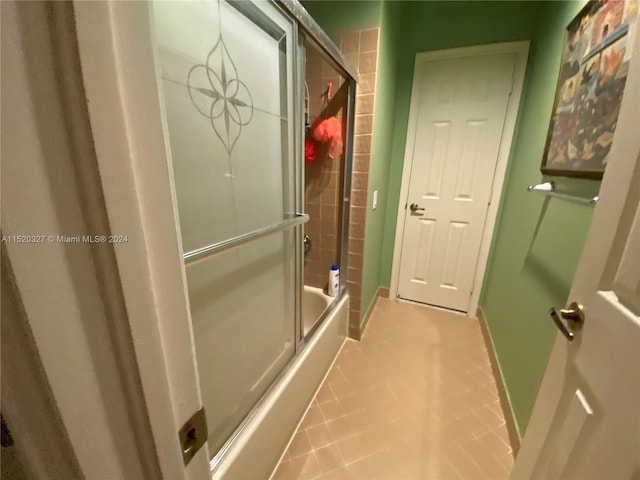 bathroom with combined bath / shower with glass door and tile floors