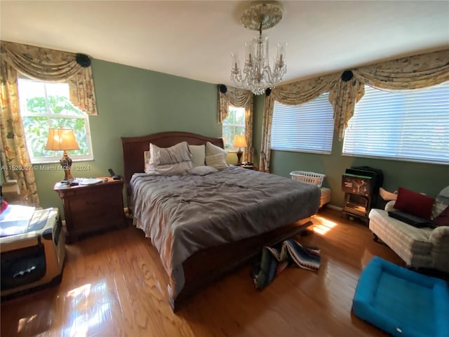 bedroom featuring multiple windows, wood-type flooring, and an inviting chandelier