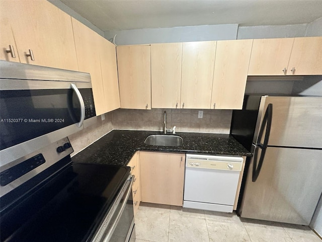 kitchen featuring appliances with stainless steel finishes, light brown cabinetry, dark stone counters, and sink