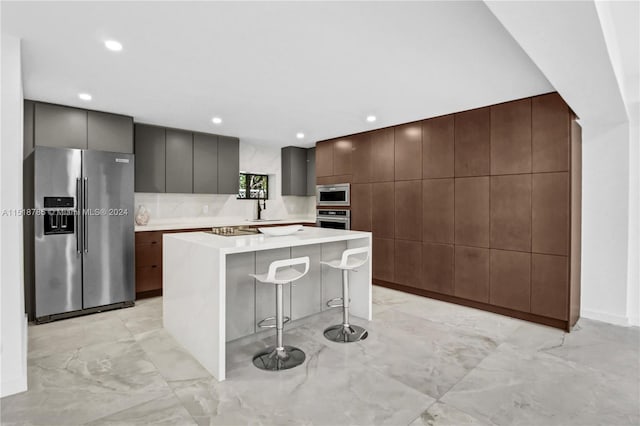 kitchen featuring a center island, stainless steel appliances, a breakfast bar, and light tile floors