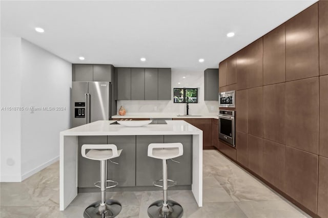 kitchen with a kitchen breakfast bar, appliances with stainless steel finishes, light tile flooring, and a kitchen island