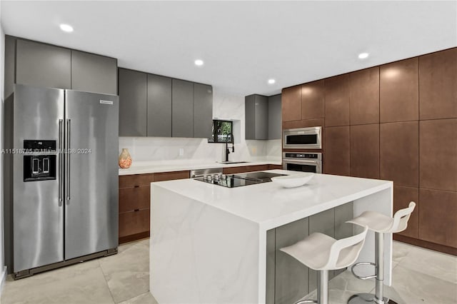 kitchen with stainless steel appliances, light tile floors, a center island, sink, and a breakfast bar