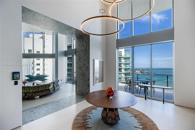 interior space featuring a high ceiling, an inviting chandelier, light tile floors, and a water view