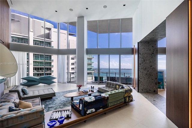 tiled living room featuring a towering ceiling and a water view