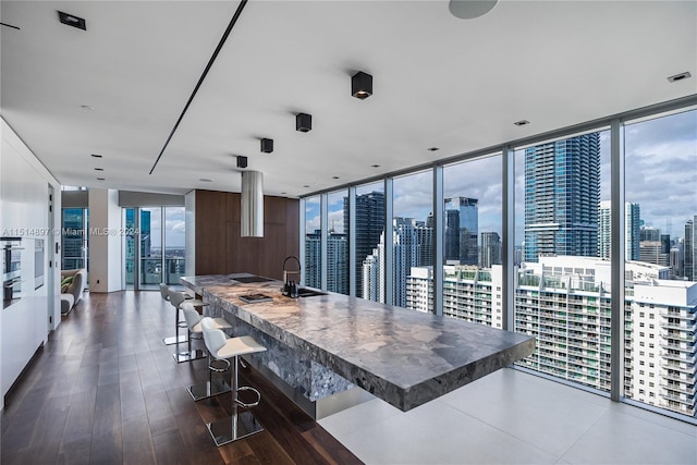 kitchen with a kitchen breakfast bar, floor to ceiling windows, sink, white cabinets, and dark hardwood / wood-style flooring