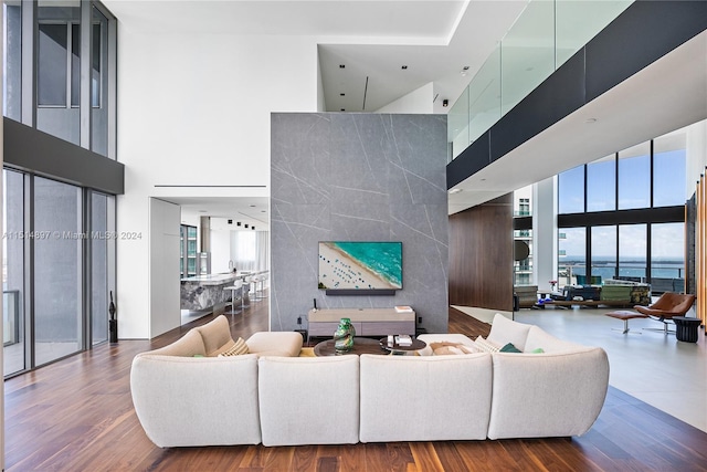 living room featuring dark hardwood / wood-style floors, a towering ceiling, and a water view