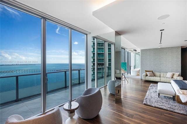 living room featuring dark hardwood / wood-style floors, a water view, and a wall of windows