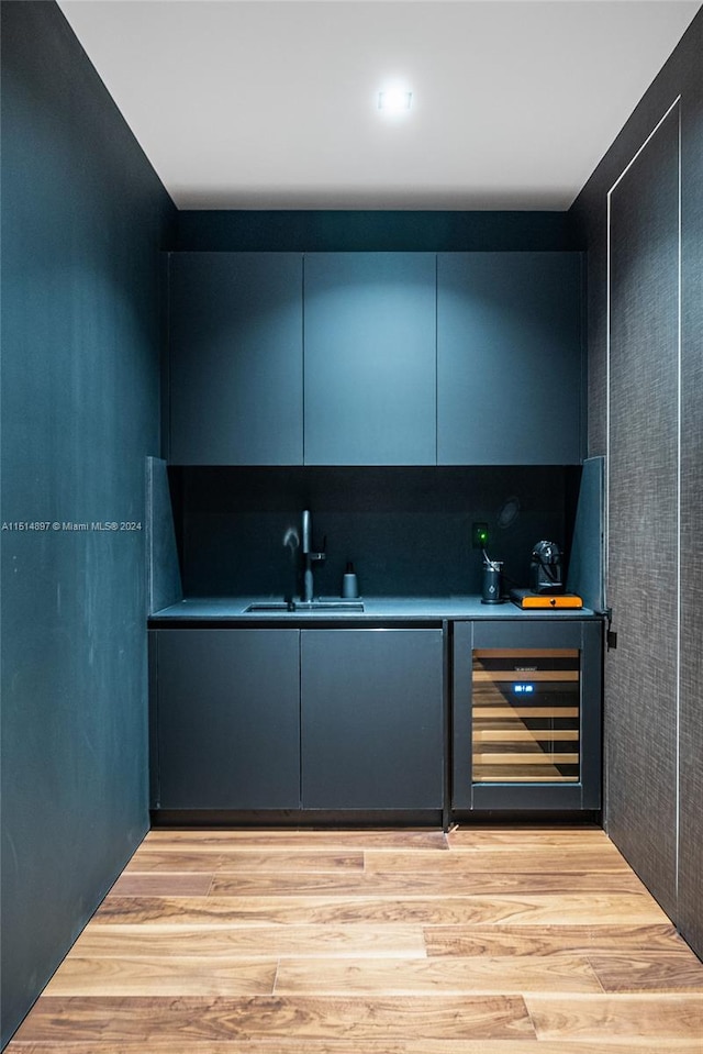 bar featuring wine cooler, sink, and light wood-type flooring