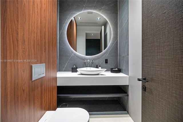 bathroom featuring tile walls, tasteful backsplash, toilet, and sink