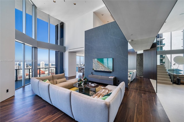 living room with a towering ceiling, dark hardwood / wood-style floors, and a wall of windows