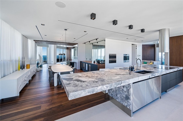 kitchen featuring white cabinets, a center island with sink, dark wood-type flooring, and sink