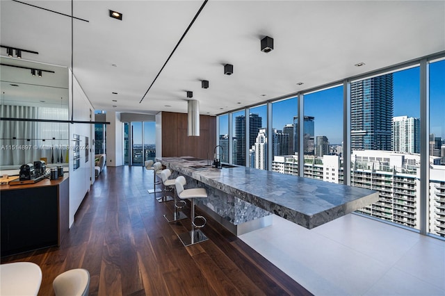 kitchen with floor to ceiling windows, a kitchen breakfast bar, dark hardwood / wood-style floors, and white cabinetry