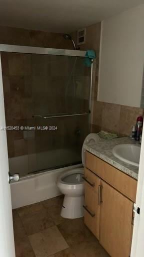 full bathroom featuring toilet, combined bath / shower with glass door, tile floors, and vanity