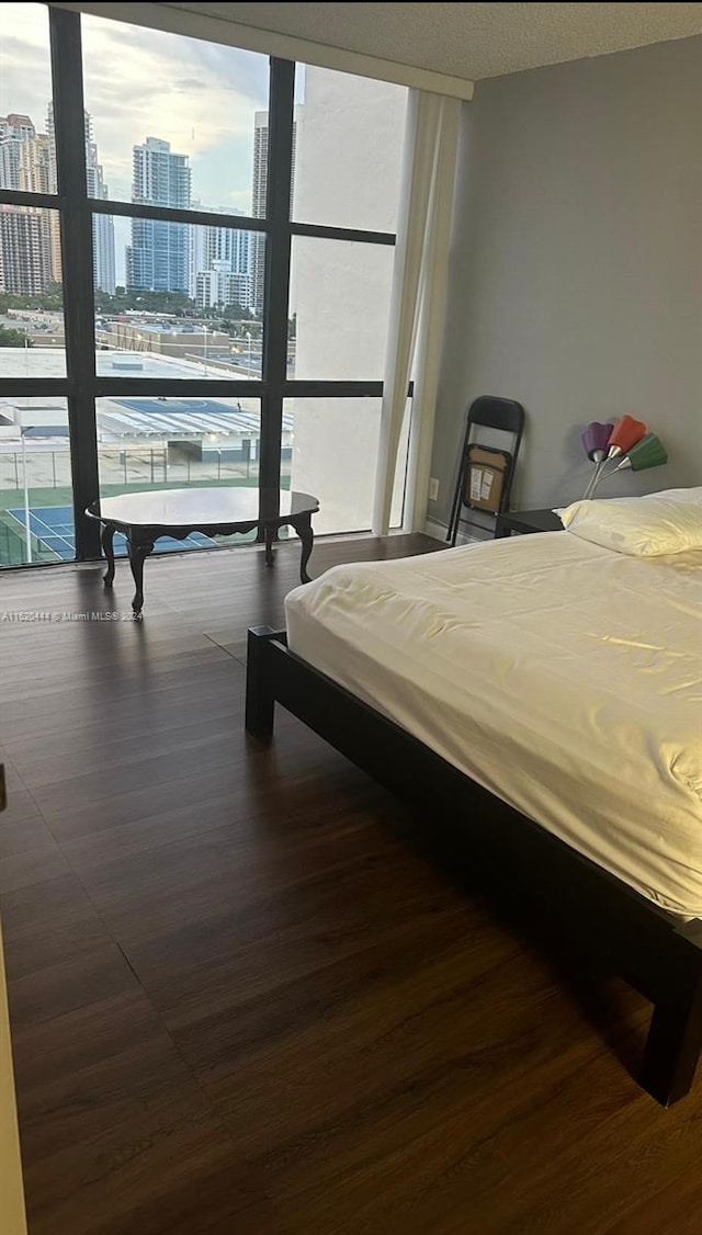 bedroom with a wall of windows and dark hardwood / wood-style floors