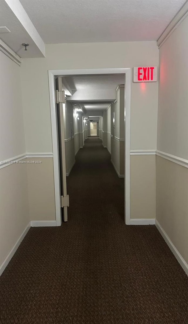 hall with dark colored carpet