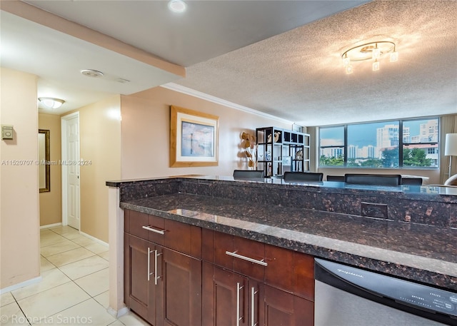 kitchen with light tile floors, dark stone counters, a textured ceiling, stainless steel dishwasher, and ornamental molding