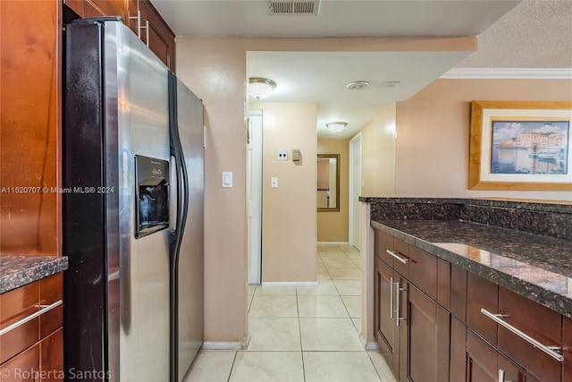 kitchen with light tile floors, a textured ceiling, ornamental molding, dark stone countertops, and stainless steel refrigerator with ice dispenser