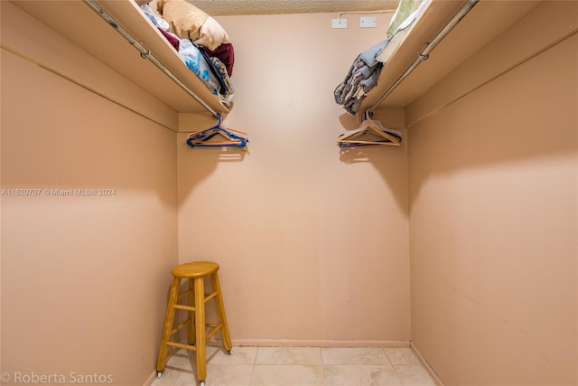 walk in closet with light tile floors