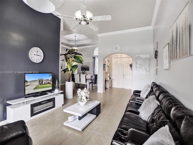 living room featuring light tile flooring, crown molding, a raised ceiling, and ceiling fan with notable chandelier