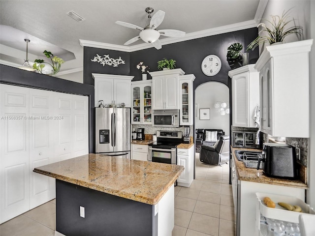 kitchen featuring ceiling fan, light tile floors, white cabinets, backsplash, and stainless steel appliances