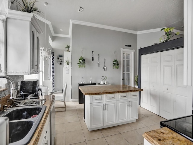 kitchen with sink, a kitchen island, white cabinetry, and crown molding